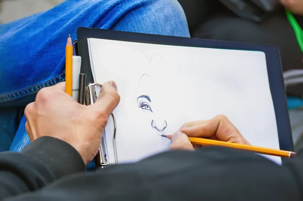 Nahaufnahme einer Männerhand mit Bleistift während der Zeichnung einer Karikatur.