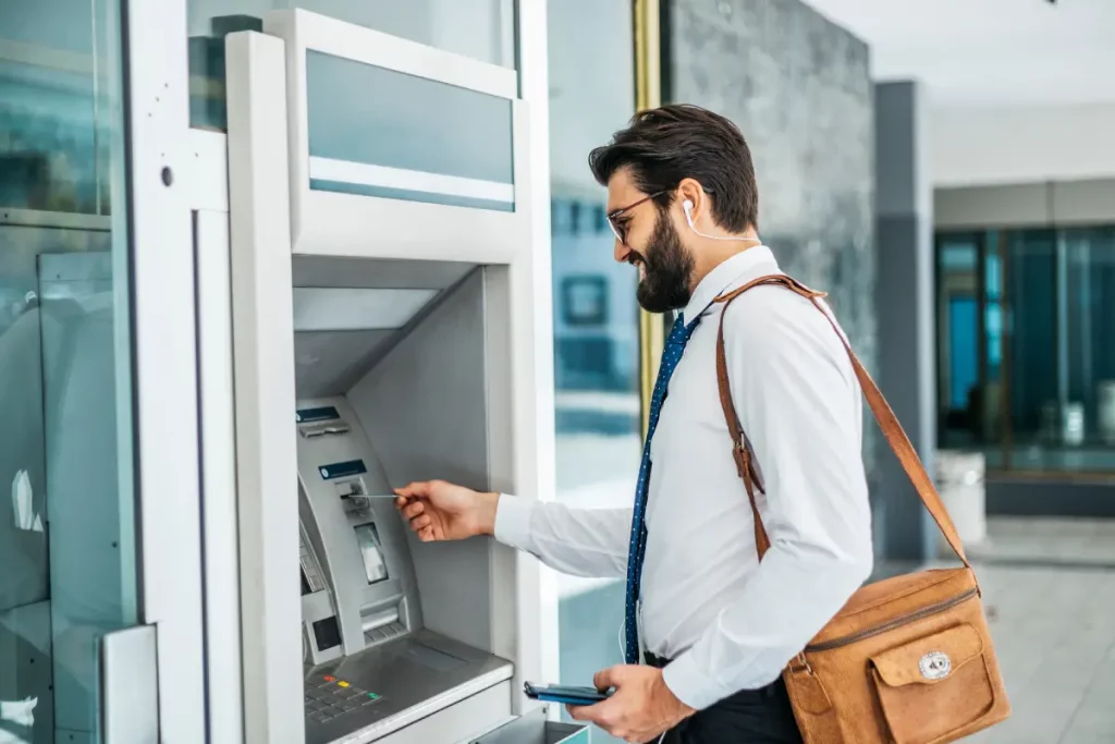 Ein Mann steht am Geldautomat und möchte seinen PIN eingeben.