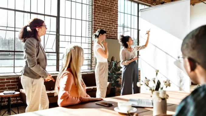 Fünf Kollegen arbeiten im Büro vor einer Leinwand zusammen.