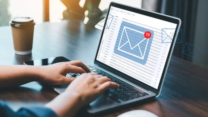Ein Laptop steht auf einem Schreibtisch. Auf dem Bildschirm ist das E-Mail-Postfach geöffnet und zeigt neue Mails an.