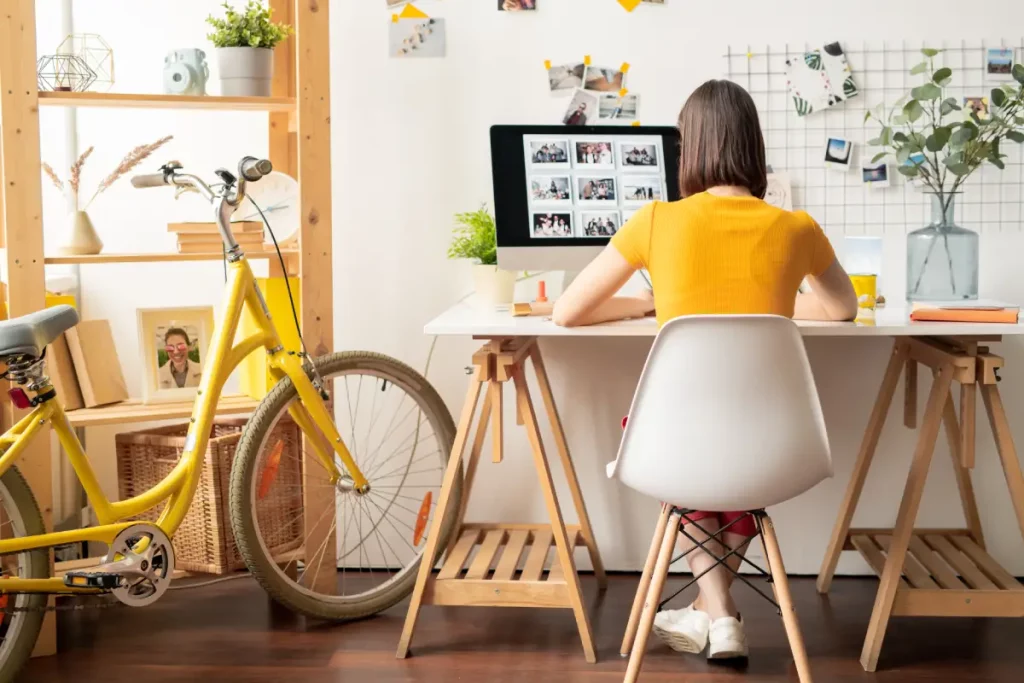 Eine Frau sitzt am Schreibtisch im Home-Office und neben ihr steht ein Fahrrad.