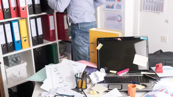 Auf dem Bild sieht man einen mit Zetteln und Dokumenten vollgepackten Schreibtisch.
