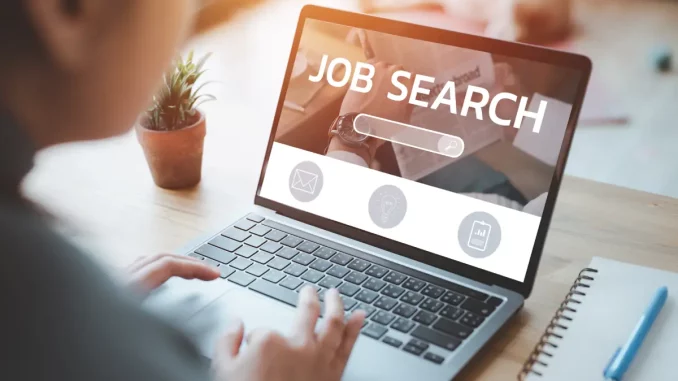 Frau am Schreibtisch sucht mithilfe ihres Laptops in einem Online-Jobportal nach einem Stellenangebot.