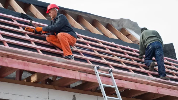 Zwei Dachdecker decken ein Dach.