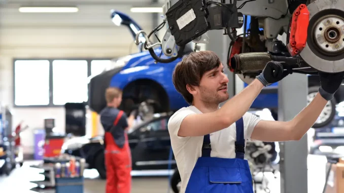 Kfz-Mechaniker schrauben während ihrer Schicht in der Autowerkstatt an Autos herum.