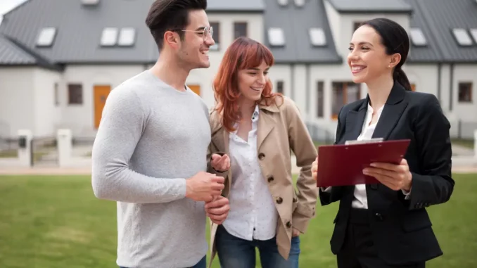 Ein Paar steht mit einer Immobilienmaklerin vor einem Haus.