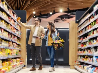 Eine Frau und ein Mann stehen im Supermarkt vor einem Regal mit vielen Produkten in unterschiedlichen Verpackungen.