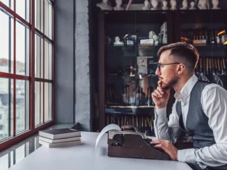 Ein Mann sitzt an seinem Schreibtisch und möchte einen Text auf der Schreibmaschine verfassen.