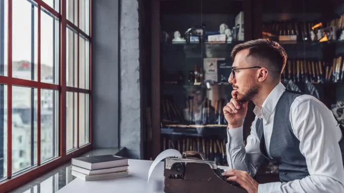 Ein Mann sitzt an seinem Schreibtisch und möchte einen Text auf der Schreibmaschine verfassen.