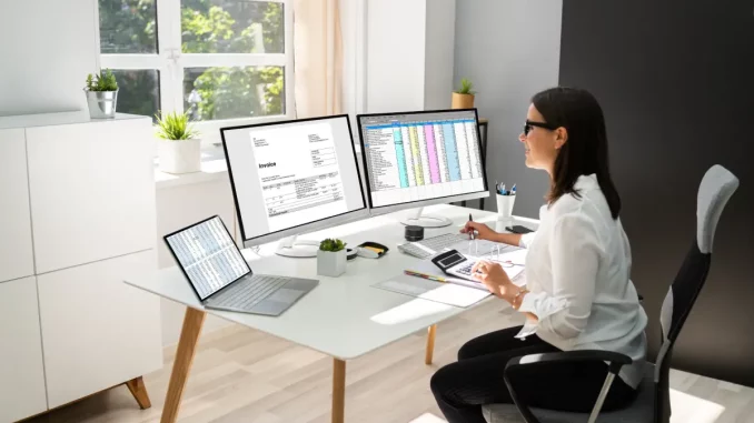 Frau sitzt am Computer im Büro und schreibt eine Rechnung.