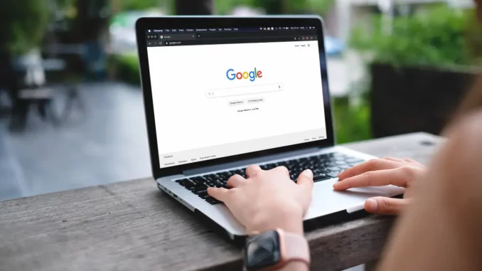 Nahaufnahme eines Laptops mit geöffneter Google-Startseite, der auf einem Tisch im Café steht.