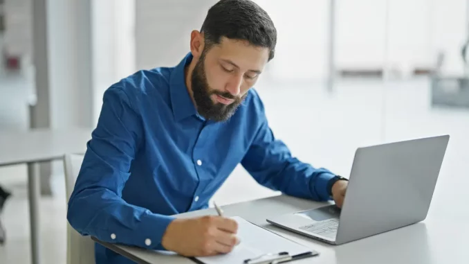 Mann schreibt etwas auf ein Blatt Papier