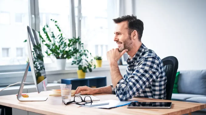 Mann sitzt am Tisch, bei der Arbeit im Homeoffice