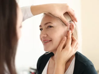 Hörgeräteakustikerin setzt Hörgerät in das Ohr einer Frau ein